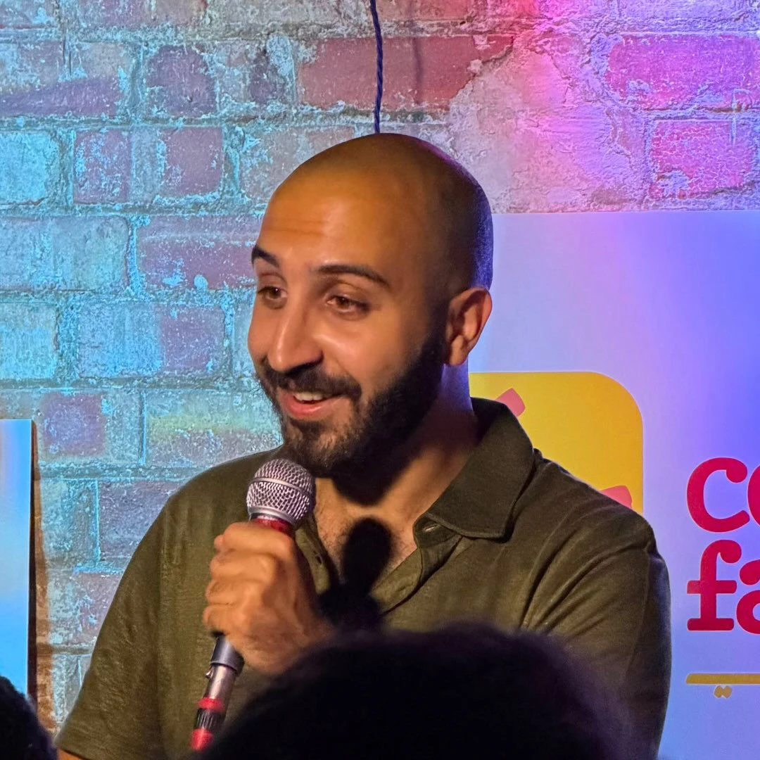 Leonardo Aoun performing stand-up comedy on stage with a microphone